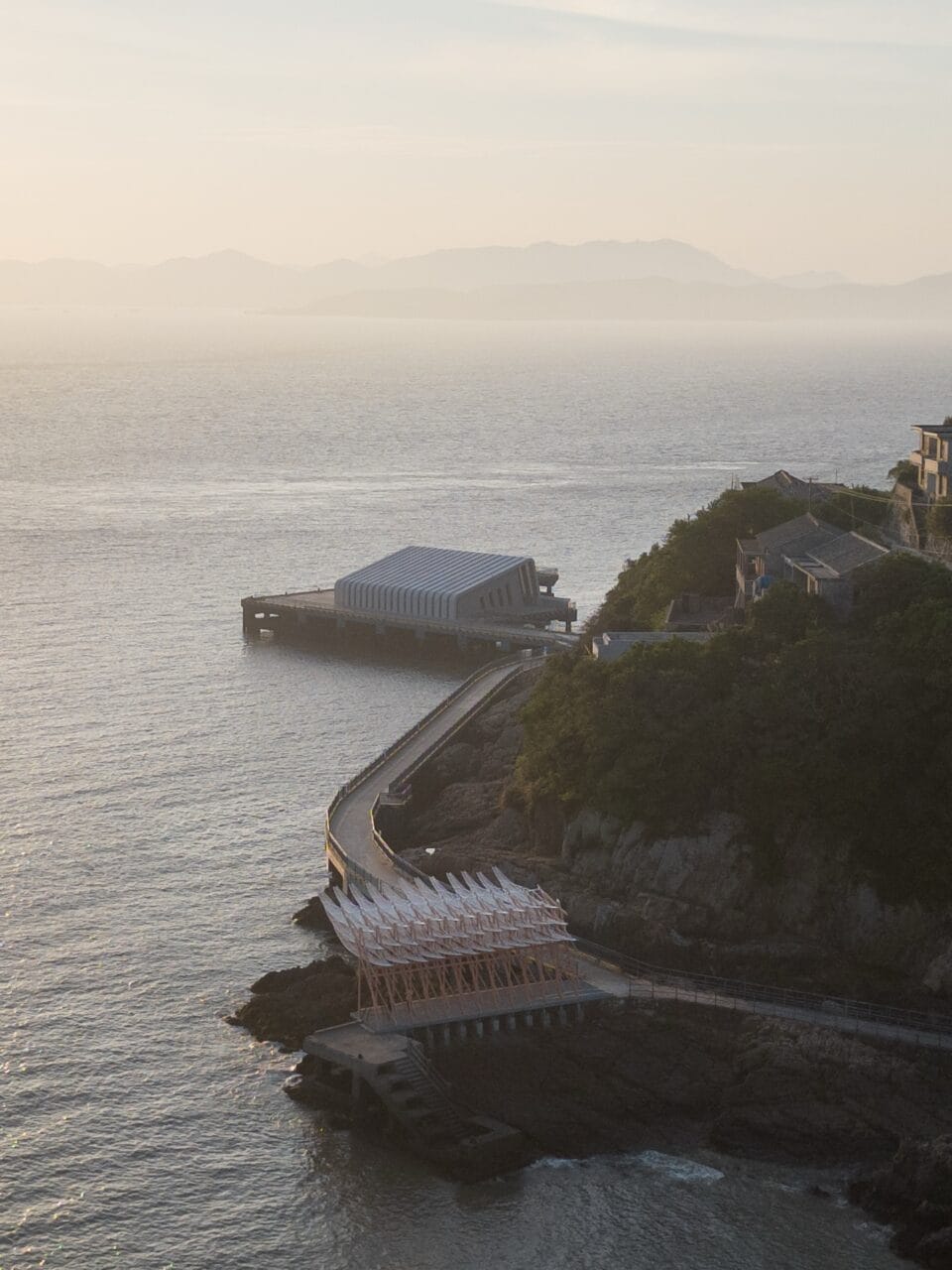 an aerial view of a seaside pavilion made of white feather-like blades