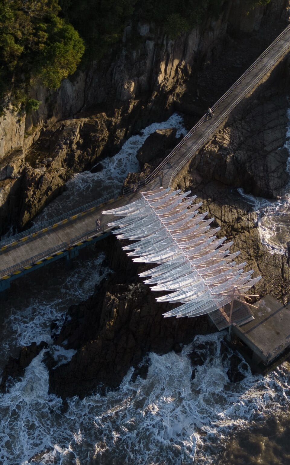an aerial view of a seaside pavilion made of white feather-like blades