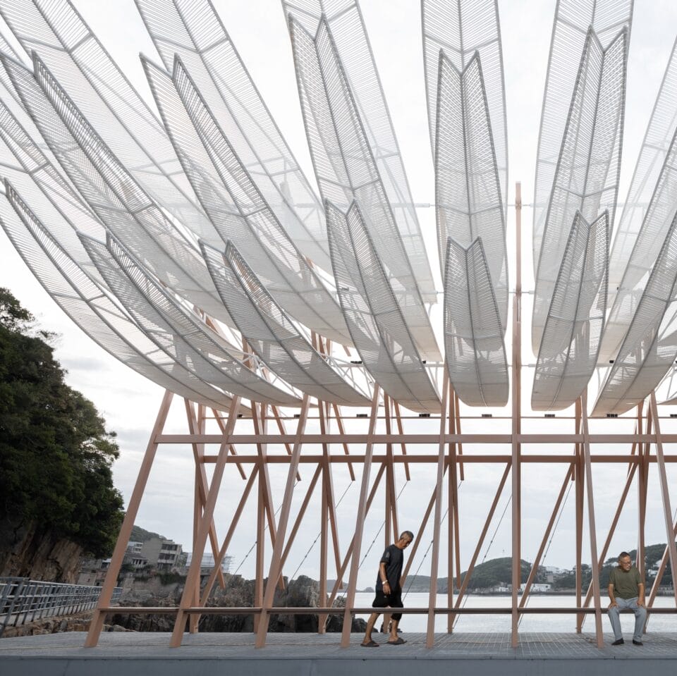 the view underneath a seaside pavilion made of white feather-like blades