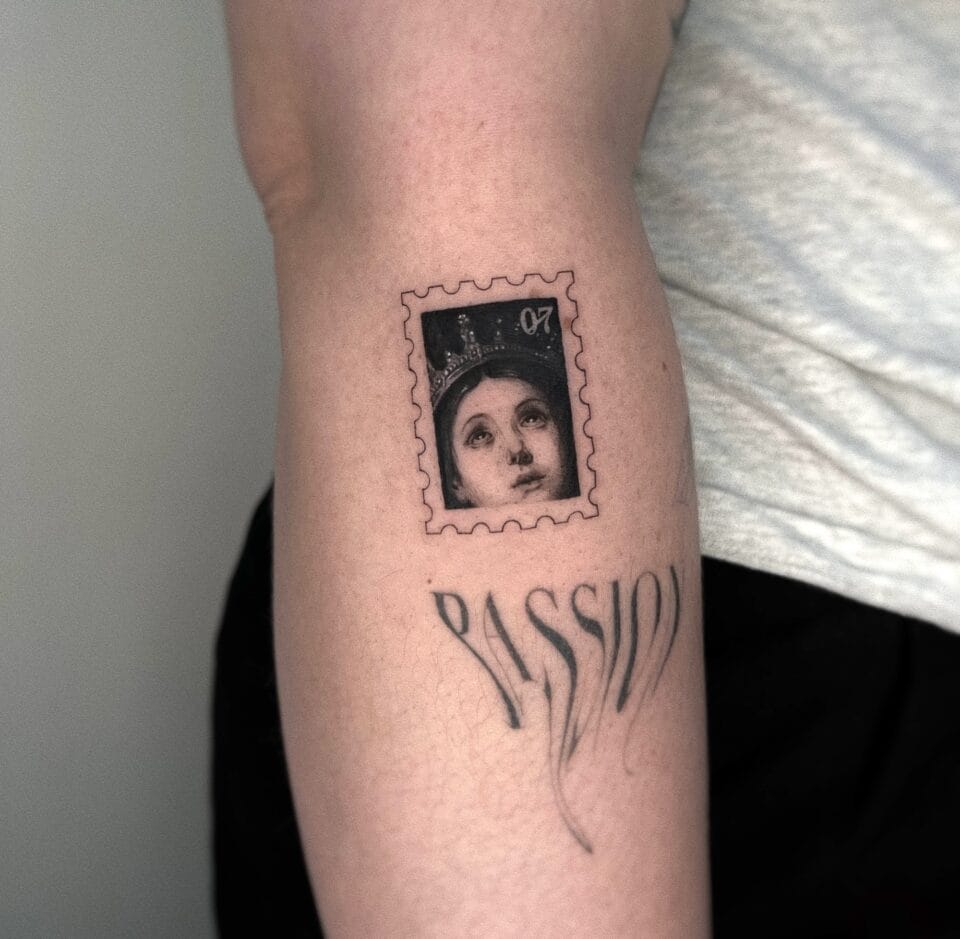 a photograph of a postage stamp-shaped tattoo on a forearm, containing a compositional detail of a religious woman's face