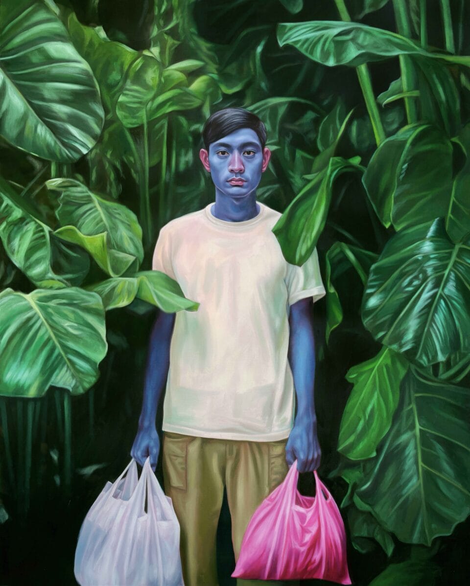 a young man, with bright blue arms and face, stands amongst tall, green foliage and holds two plastic bags