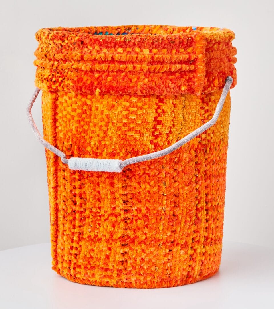 a vessel shaped like a 5 gallon bucket, made from woven orange pipe cleaners