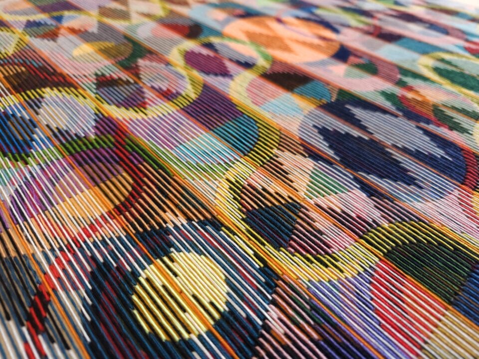 a detail of an abstract, geometric thread composition on a wood panel