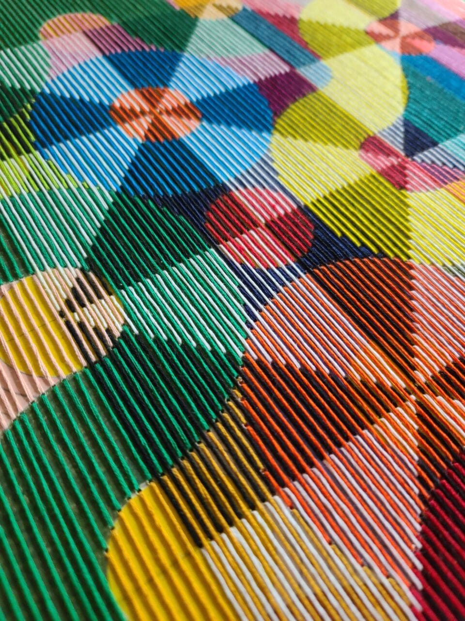 a detail of an abstract, geometric thread composition on a wood panel