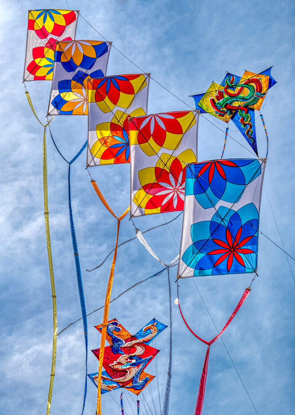 a series of vibrant patterned kites in the sky