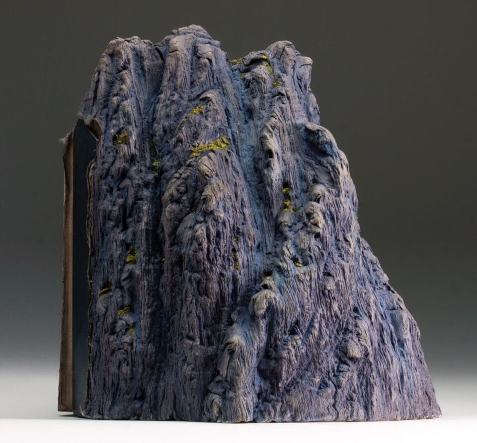 a sculpture made from a set of large books, covers removed to reveal the stitched binding, which has been water-blasted to soften and manipulate the pages into a form resembling a large mountain