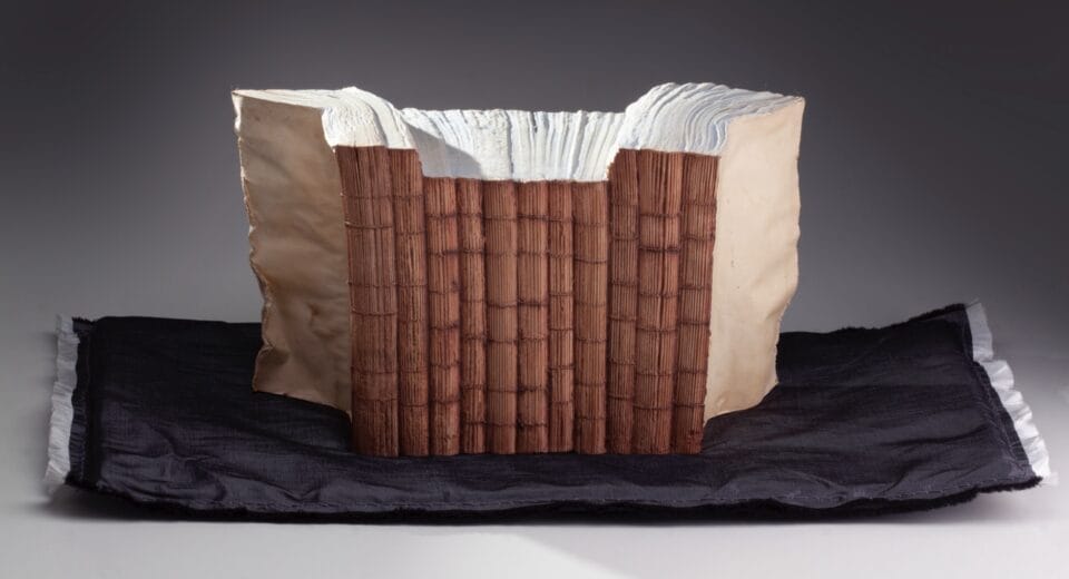 a sculpture made from a set of large books, covers removed to reveal the stitched binding, which has been water-blasted to soften and manipulate the pages into a form resembling a large mountain