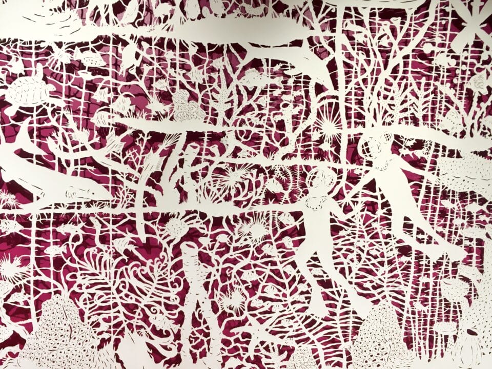 a detail of a composition of botanic motifs and scuba divers made of cut paper on a red background