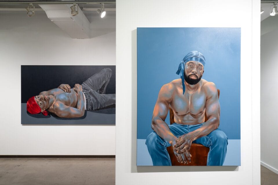 two nearly life-size oil portraits of Black men gazing directly at the viewer, on view in an art fair booth