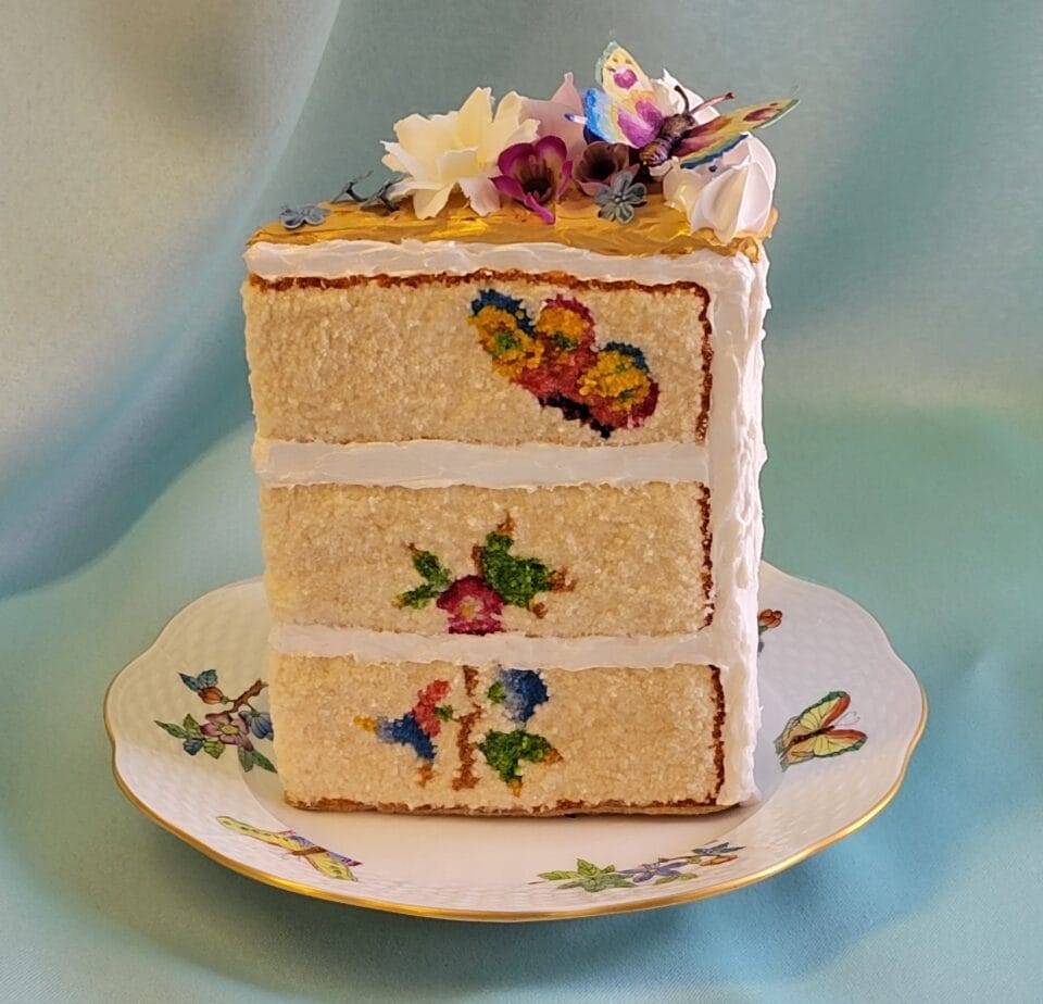 a small sculpture of a slice of layer cake, with realistic frosting details and embroidery on that looks like the texture of fluffy sponge