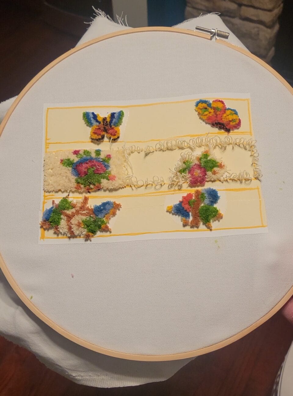am embroidery hoop with three cream-colored compartments with floral details, emulating the side of a sliced piece of layer cake