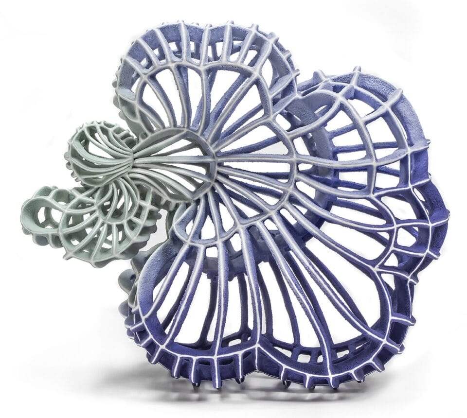 an abstract ceramic sculpture with a blue and green gradient in porcelain, featuring numerous spokes and irregular concentric shapes