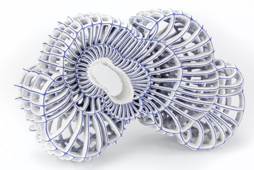 an abstract ceramic sculpture with blue porcelain and white flocked-like surfaces with numerous spokes and irregular concentric circles with an opening through the middle of the piece
