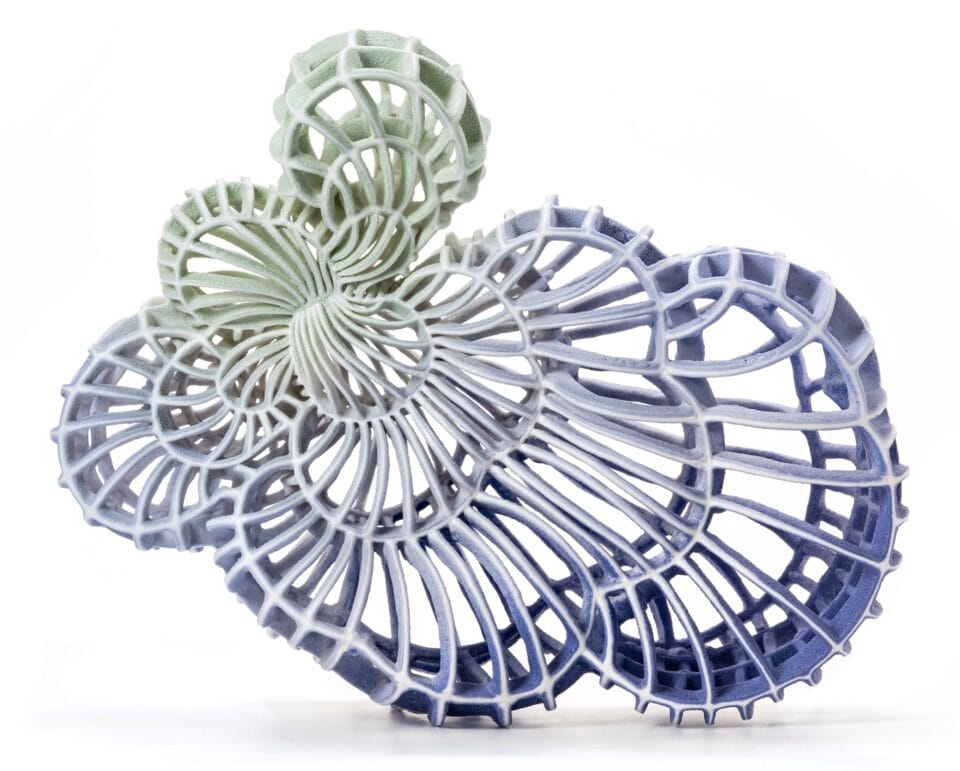 an abstract ceramic sculpture with a blue and green gradient in porcelain, featuring numerous spokes and irregular concentric shapes