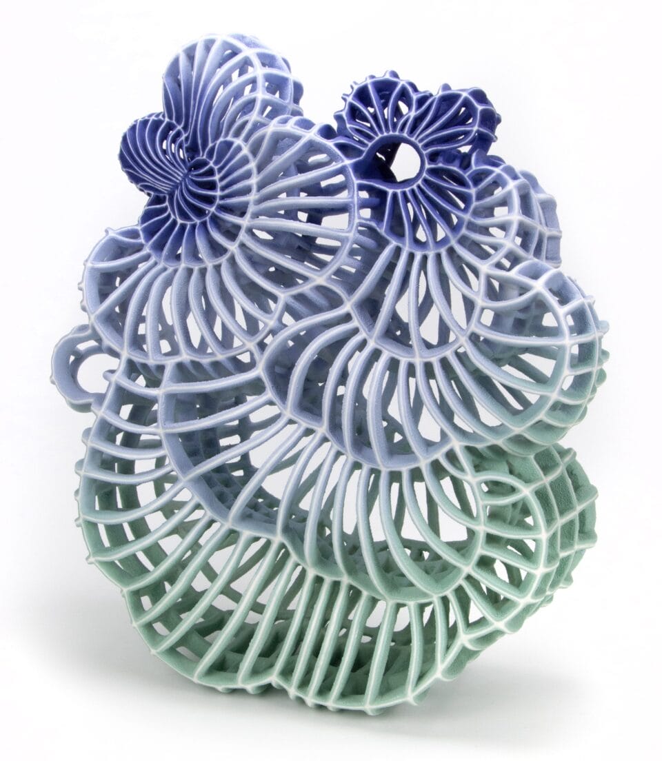 an abstract ceramic sculpture with a blue and green gradient in porcelain, featuring numerous spokes and irregular concentric shapes