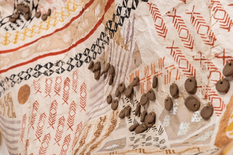 a detail of a large, patchwork wall hanging made from kapa, or barkcloth, dyed with numerous natural dyes