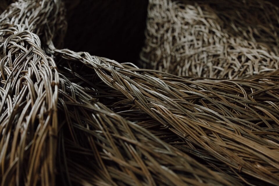 a detail of a sculptural installation that moves through an architectural space, made of woven willow branches