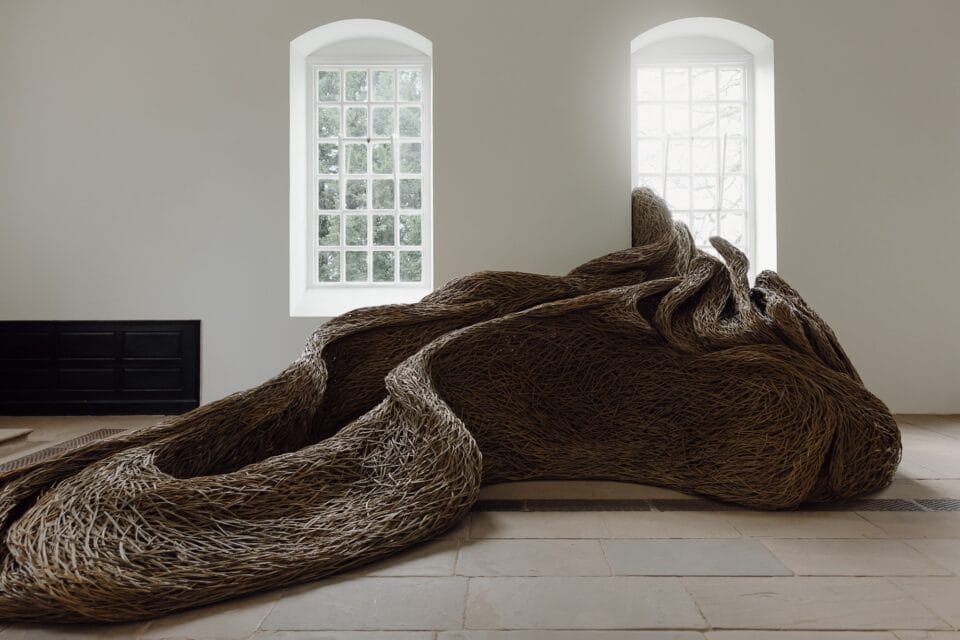 a sculptural installation that moves through an architectural space and interacts with windows, made of woven willow branches