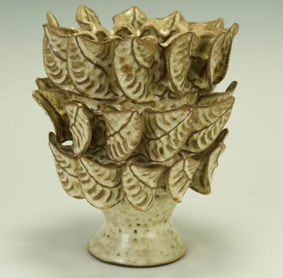 a beige ceramic vessel surrounded by hand-pinched leaves