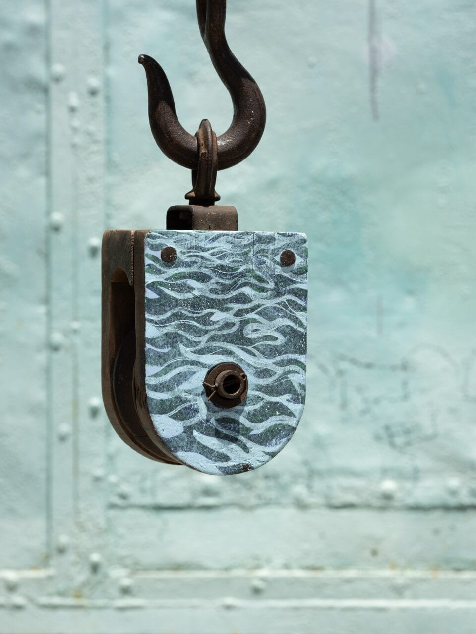 an antique marine pulley with a painting of a wave pattern on the front