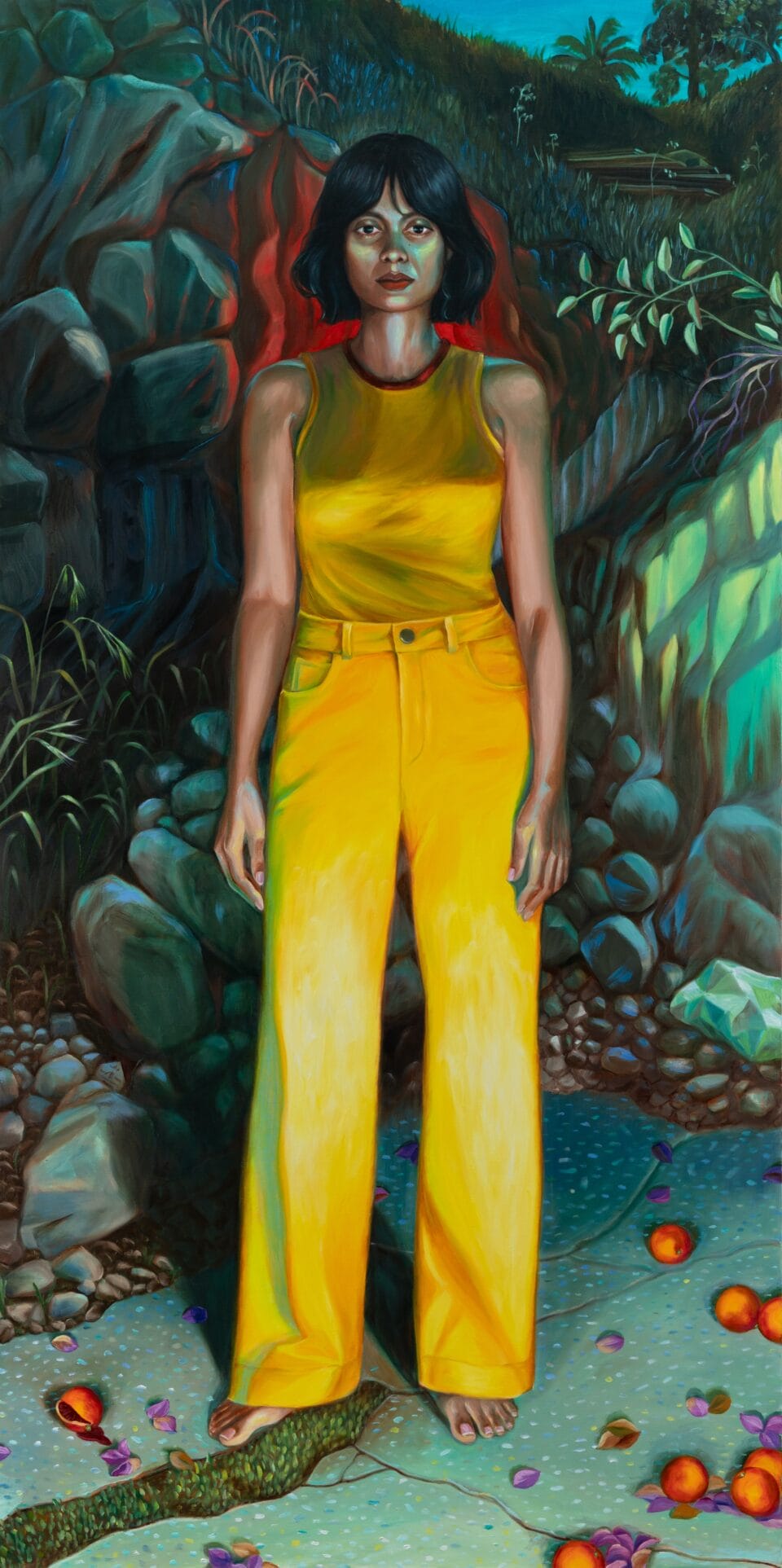 a woman in a yellow tank top and yellow pants stands barefoot against a green and blue tinged rocky background