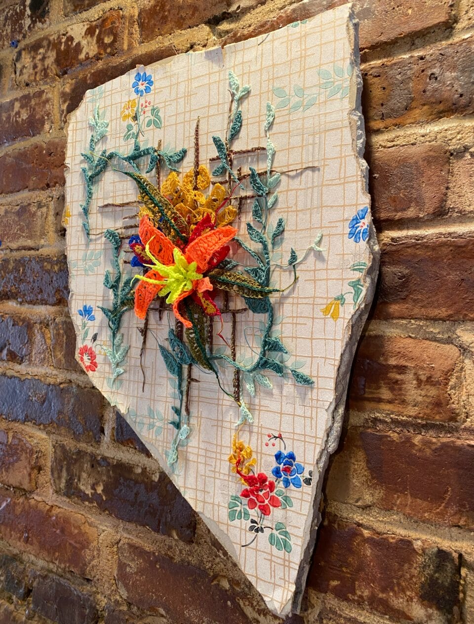 a delicate crocheted flower on a patterned shard