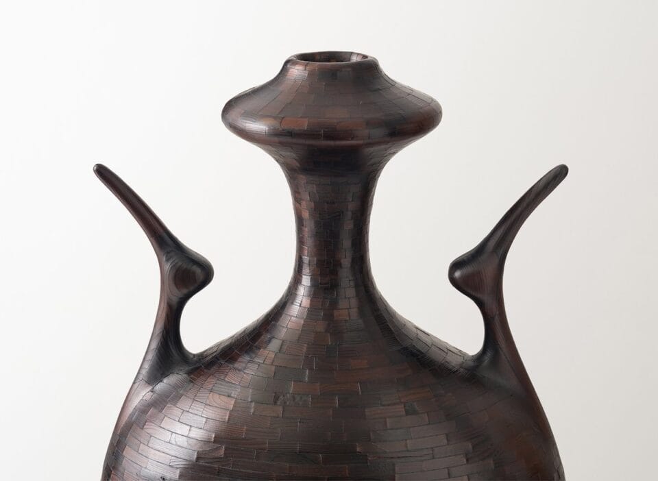 a detail image of a wooden vessel made of stacked pieces in varied colors