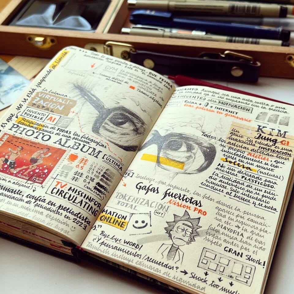 a small sketchbook with elaborately designed travel notes and drawings, on a table with artmaking tools like pens and ink