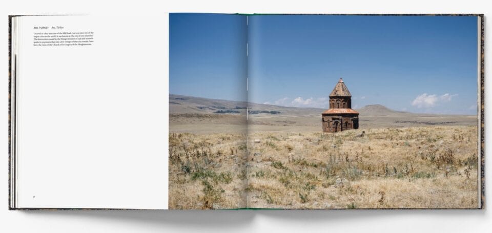 a spread from the book 'The Silk Road: A Living History' showing a small wooden building in a broad expanse of grassland on a sunny day