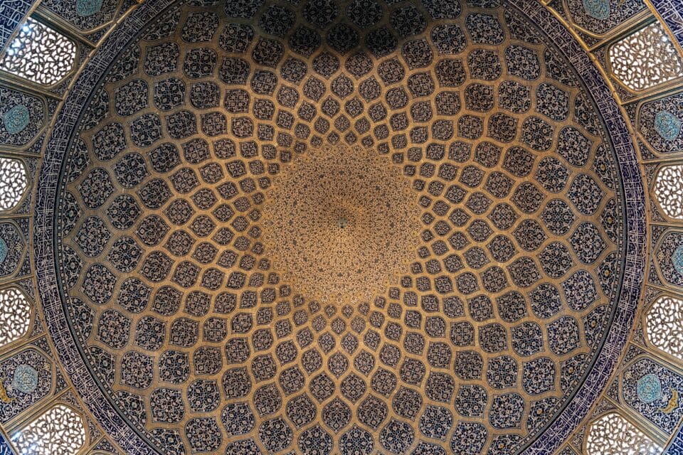 a photograph looking up at the detailed geometric, mosaic ceiling of a mosque