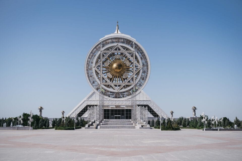 a photograph of a modernist building in a large plaza against a blue sky, with a large circular detail on top