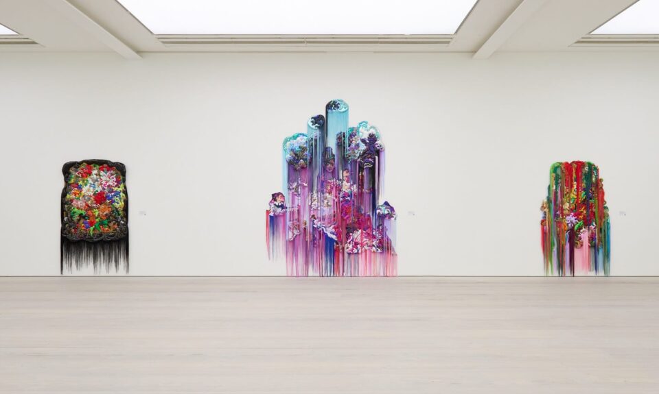 an installation view in a large, white-walled gallery space of three large-scale wall installations