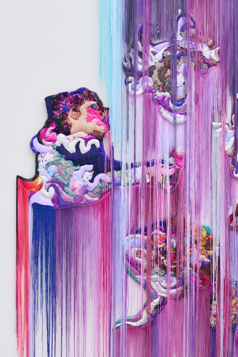 a detail of a monumental, abstract wall installation that appears to be cascading in purple, teal, and pink hues