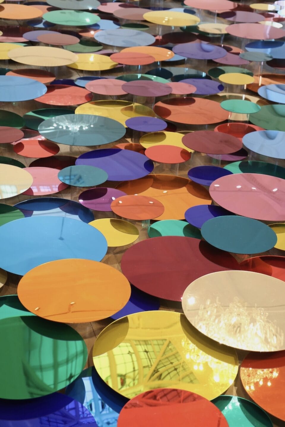 a floor installation of numerous shiny, colorful circles